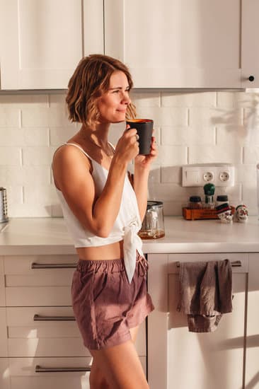 Happy woman drinking coffee in kitchen