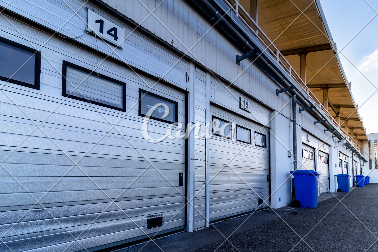 Numbered Garage Doors With Blue Trash Cans Between Them Photos