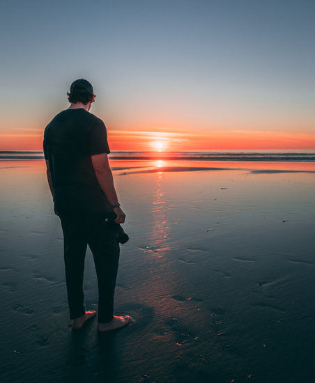 Man Standing on Beach during Sunset