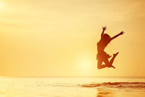 Happy woman jumps lake water sunset