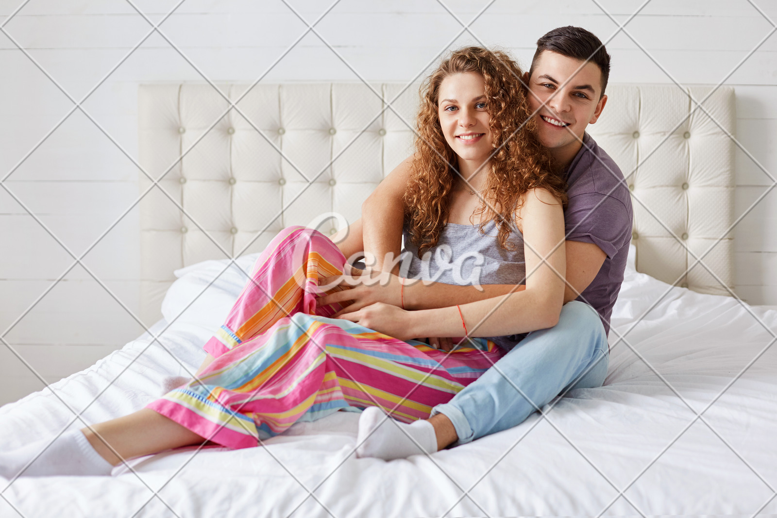 Young Family Couple Sit And Embrace On Comfortable Bed