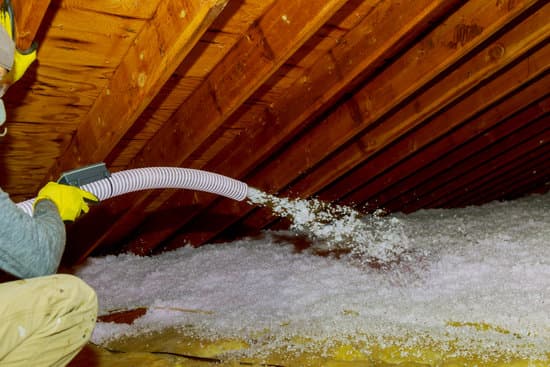 Technician Spraying Blown Fiberglass Insulation Between