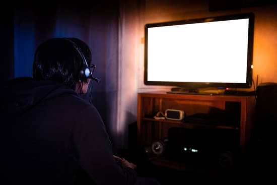 Young Male Gamer With Glasses And Headset Playing Video Game