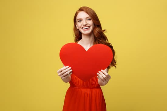 Portrait Happy Woman Holding a Heart Symbol on Yellow Background