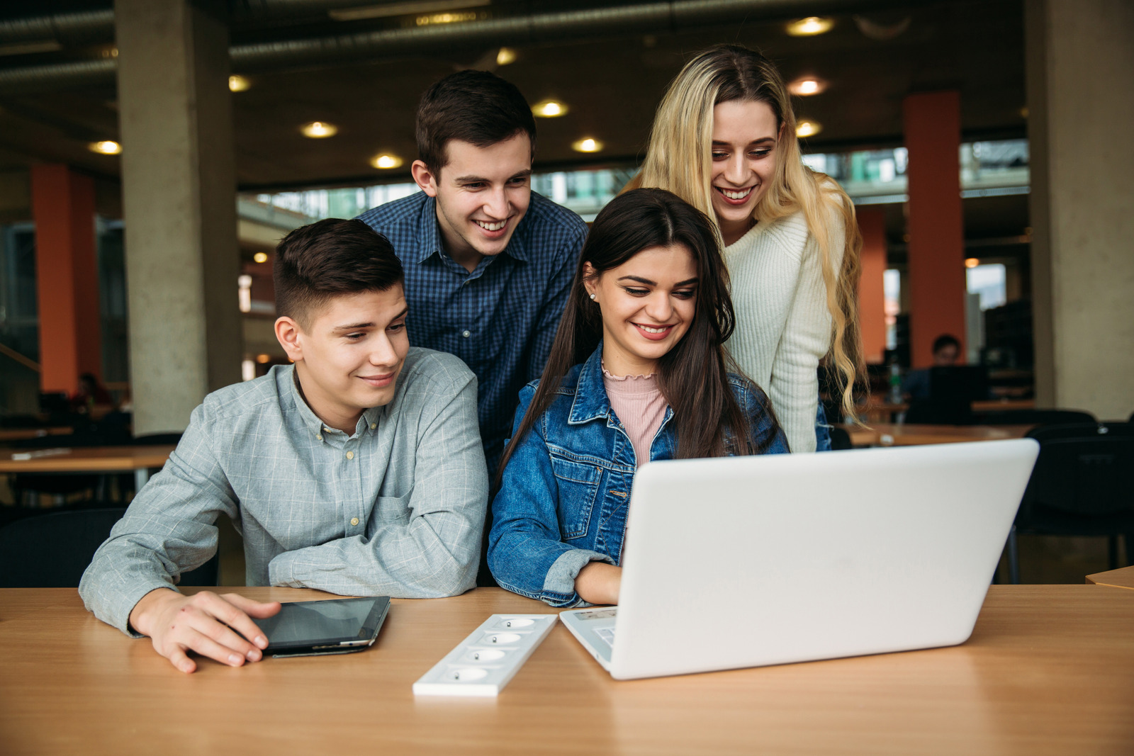 学校の図書館で勉強している大学生のグループ、女の子と男の子がラップトップを使用してインターネットに接続しています