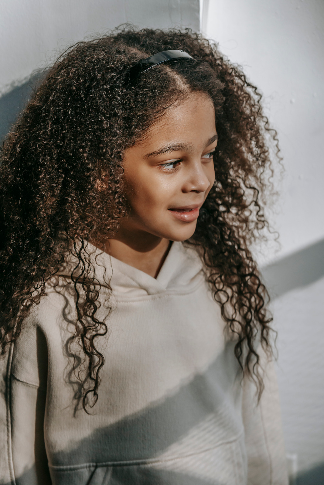 Cheerful black girl standing near white wall and looking away - Photos ...