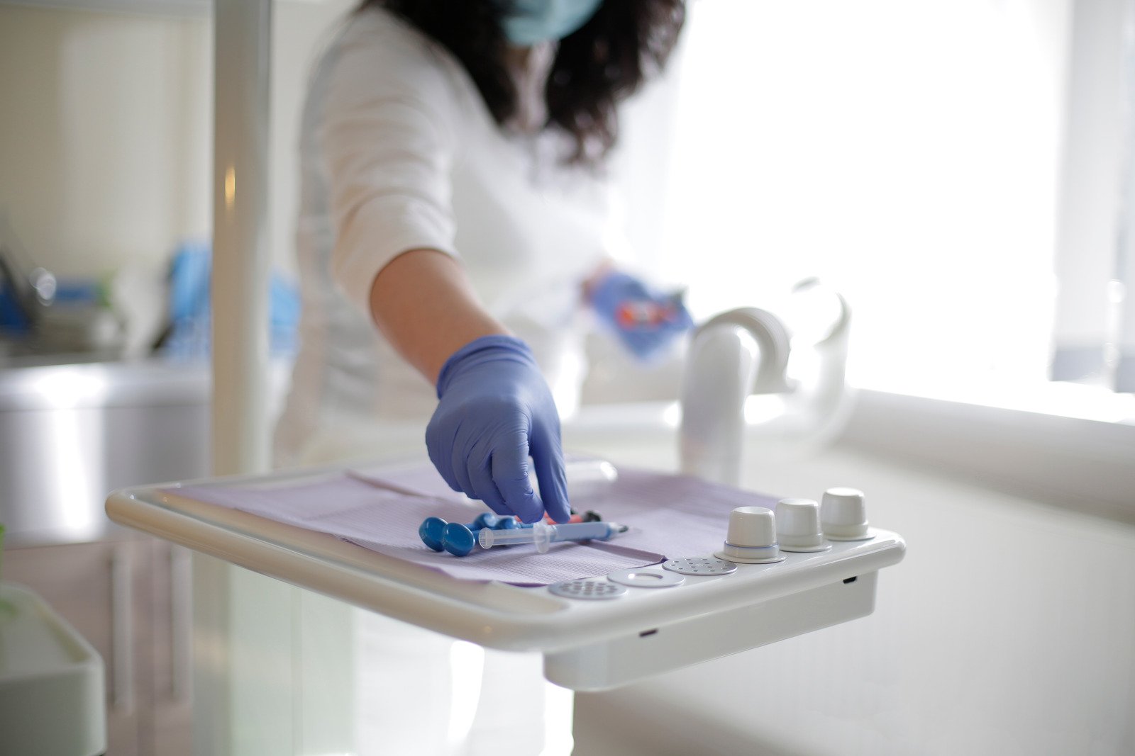 Crop anonymous female dentist preparing medical tools on dentist table